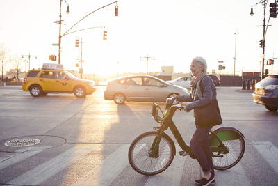 Side view of senior woman walking with bicycle on street