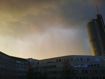 Low angle view of office building against cloudy sky