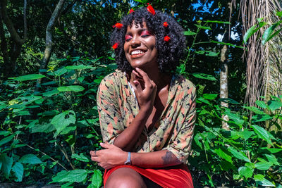 Portrait of smiling young woman sitting against plants