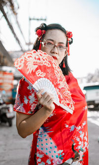 Portrait of smiling young woman holding fan