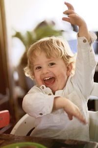 Portrait of cheerful boy gesturing while sitting at table