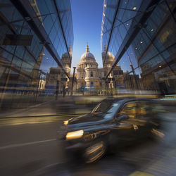 Blurred motion of cars on road in city against sky