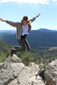Full length of woman standing on rock against mountain