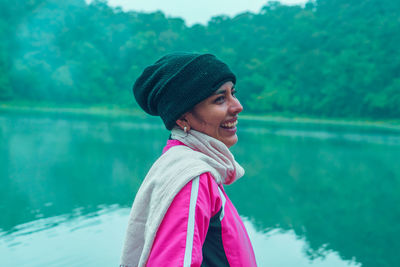 Portrait of smiling woman standing against lake