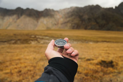 First-person view of a male traveler s hand holding a magnetic compass against the backdrop 