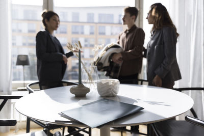 Agreement files on table with saleswoman discussing with clients in background at home