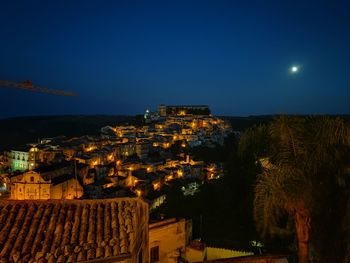 Illuminated buildings in city against clear sky at night