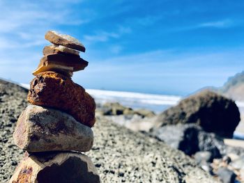 Close-up of stone stack on rock at beach against sky