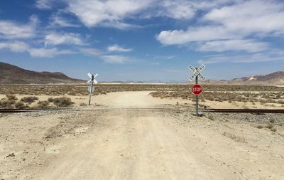 Road sign in desert against sky