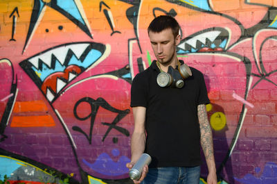 Full length of young man standing against graffiti wall