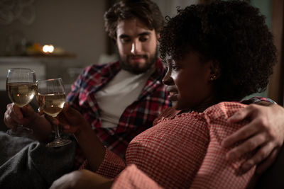 Multiethnic couple chilling on sofa with wine