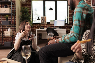 Portrait of smiling friends using mobile phone while sitting in cafe