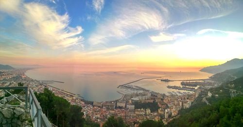 High angle view of buildings and sea against sky during sunset