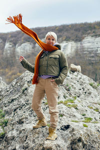 Woman stands on a rock in autumn in warm clothes