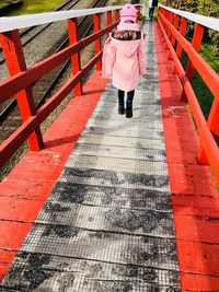 Rear view of woman walking on footbridge