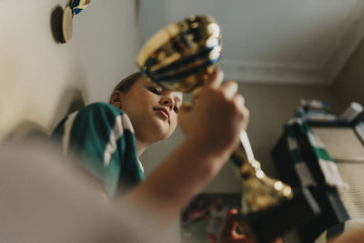 Dedicated girl holding trophy while sitting at home