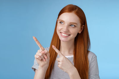 Portrait of a smiling young woman against blue background