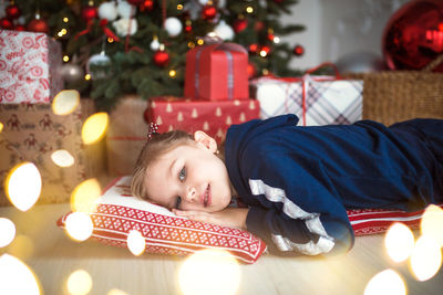 Boy lying on illuminated christmas tree at home