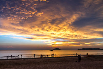 Silhouette people on beach against sky during sunset