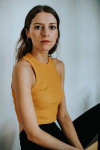 Portrait of young woman sitting by wall
