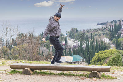 Happy mature asian man in casual clothes is cheerfully dancing on the wooden bench 