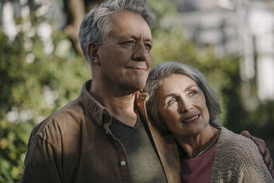 Portrait of confident senior couple in garden of their home in autumn