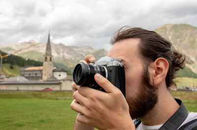 Young man photographing from camera on land