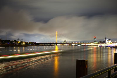 Illuminated bridge over river in city at night