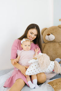 A young mother holds her little daughter in her arms in the children's room, they play