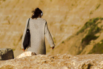 Rear view of woman perching on rock