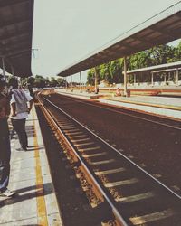 People waiting at railroad station platform against sky