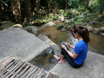 Full length of woman sitting on rock