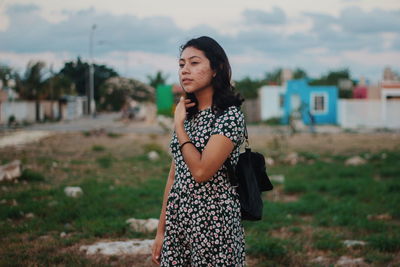 Young woman looking away while standing on field