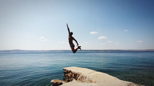 Silhouette of woman jumping on beach