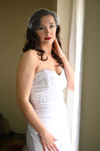 Young woman looking away while standing against wall