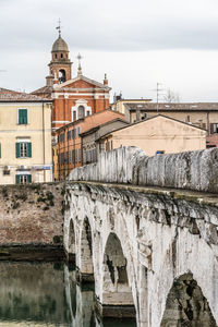 View of old building by canal against sky