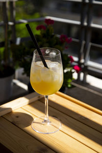 Yellow cocktail in vine glass with black stick under the sun. chilling on the balcony