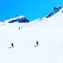 People skiing on snowcapped mountain against clear sky