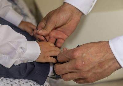 Cropped hands of father tying son shoelace