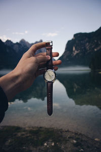 Close-up of hand holding water against sky