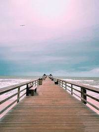 Pier over sea against sky during sunset