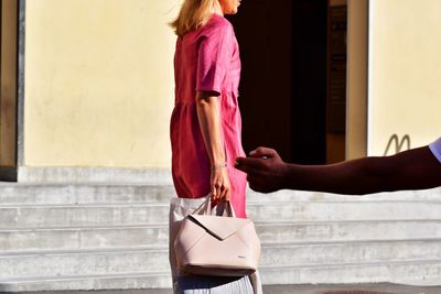 Midsection of woman holding umbrella while standing against wall