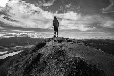 Male hiker standing on cliff against sky