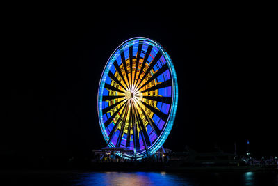 Illuminated ferris wheel against sky at night