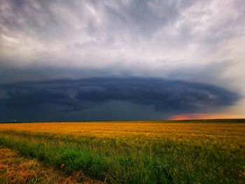 Scenic view of field against cloudy sky