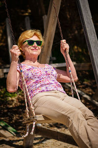 Senior woman joyfully swinging on a swing and having fan