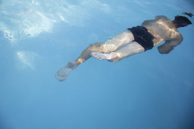 Rear view of shirtless young man swimming in sea