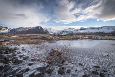 Scenic view of lake by snowcapped mountains against sky