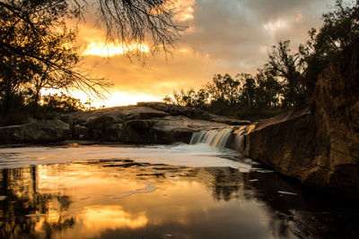 Scenic view of river against sky at sunset