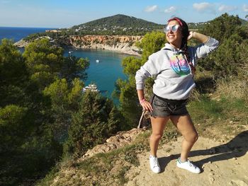 Full length of smiling young woman standing on mountain